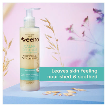 Aveeno Calm + Restore Nourishing Oat Cleanser bottle on a pastel background with text about skin care benefits.